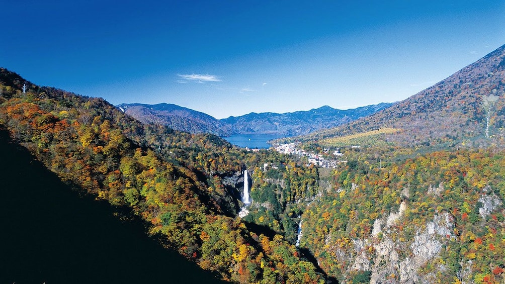 Ariel view of waterfall amongst cliffs and tree over mountains in Nikko