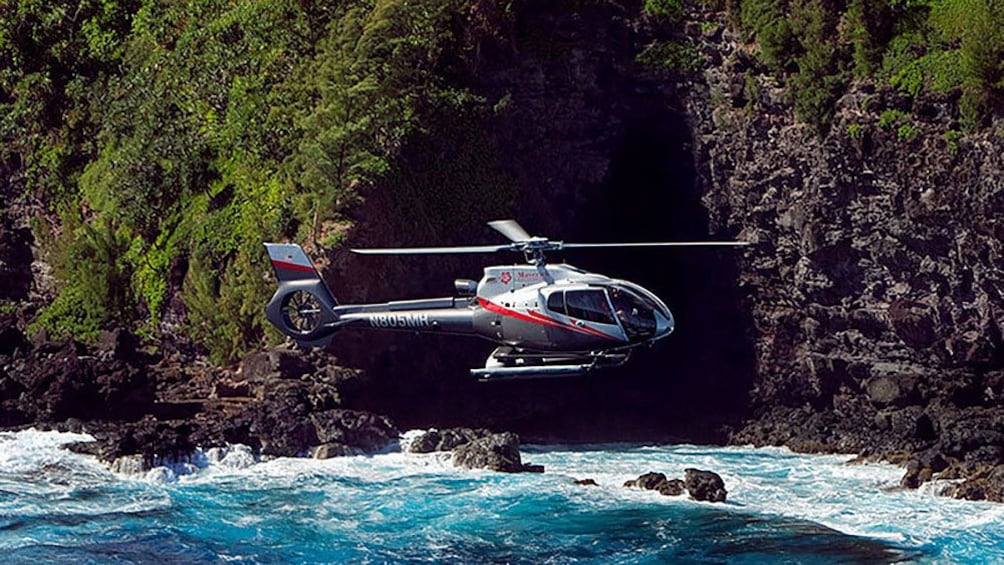 Helicopter flying near sea cave in Hana