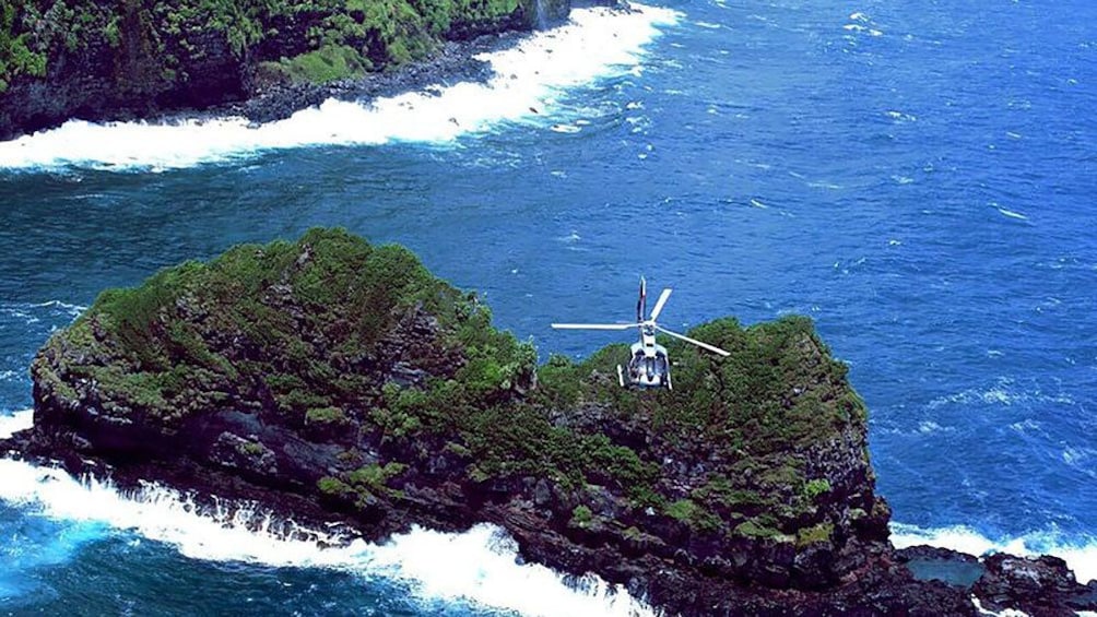 Helicopter flying over rock formations in ocean off of Hana