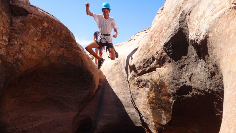 Group member jumping from rock to water below in Moab