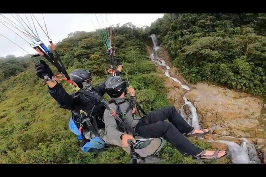 Paragliding flight over a valley of mountains and waterfalls + video