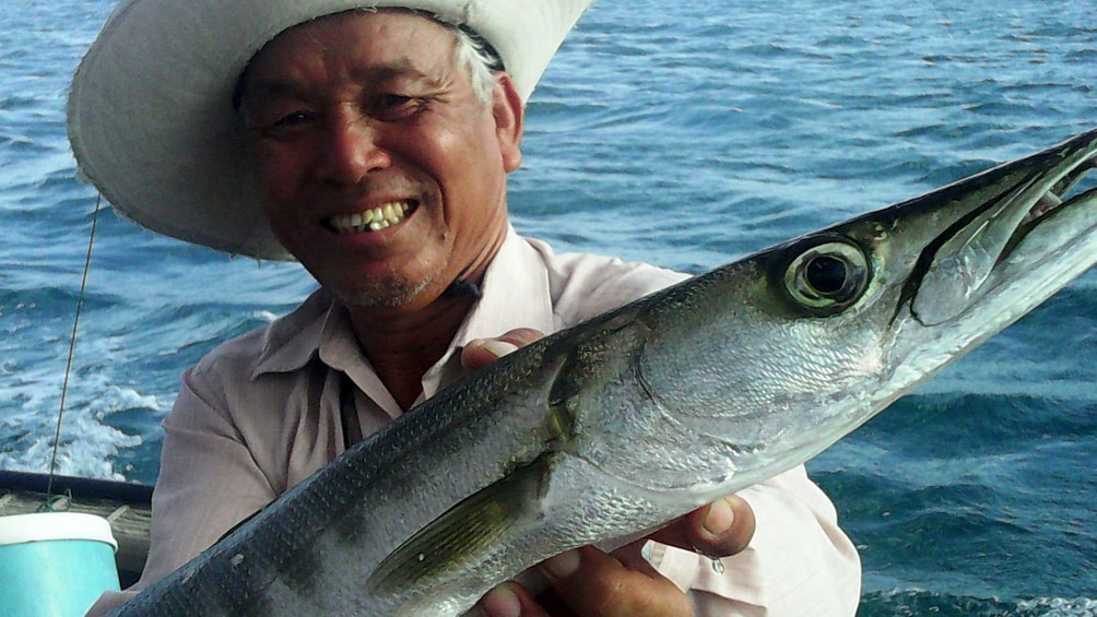 Man holding a caught fish in a boat in Da Nang