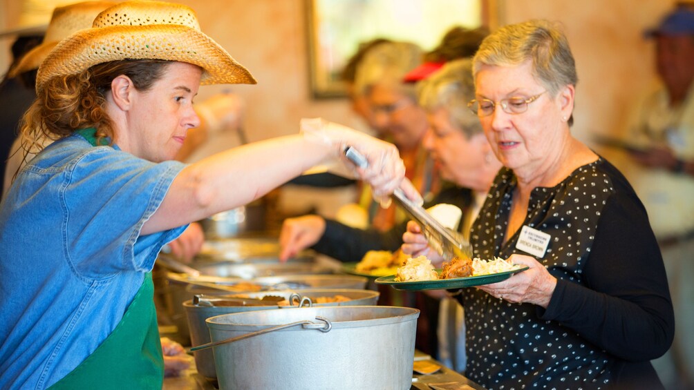 Show item 3 of 5. Woman being served food in a line.
