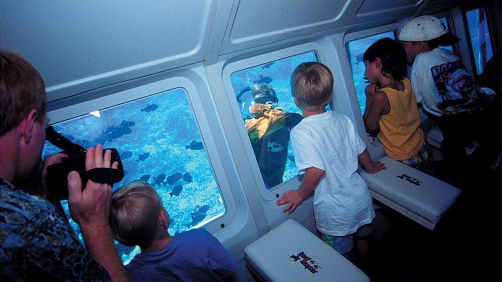 Kids looking out the window at scuba diver in the Glassbottom Reef explorer in Maui