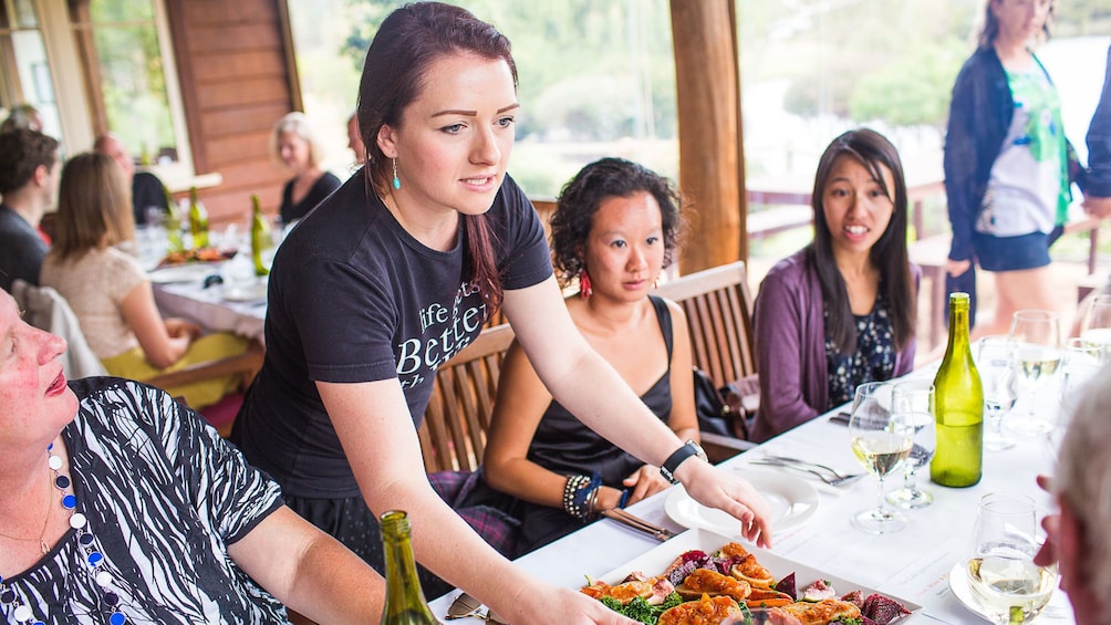 Waitress placing food on table at The Lake House restaurant in Denmark, Australia