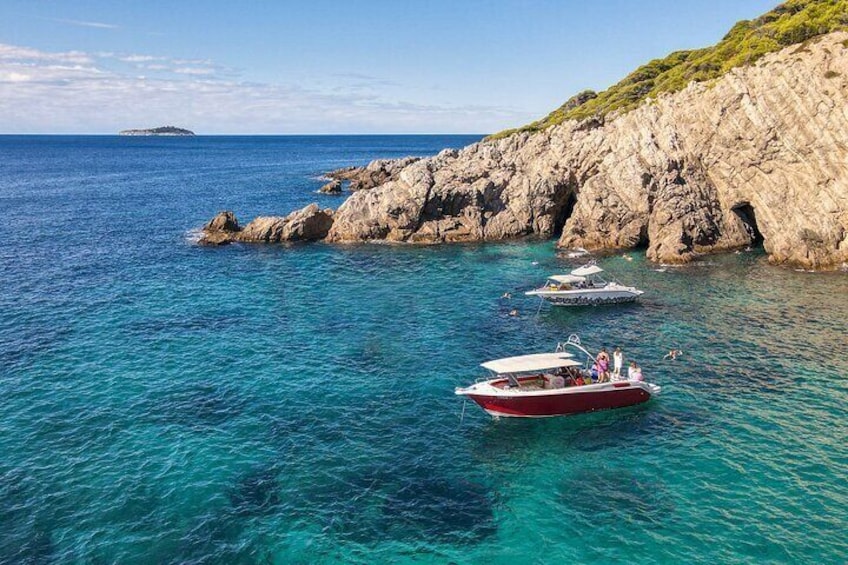 Speed boats anchored in front of green cave