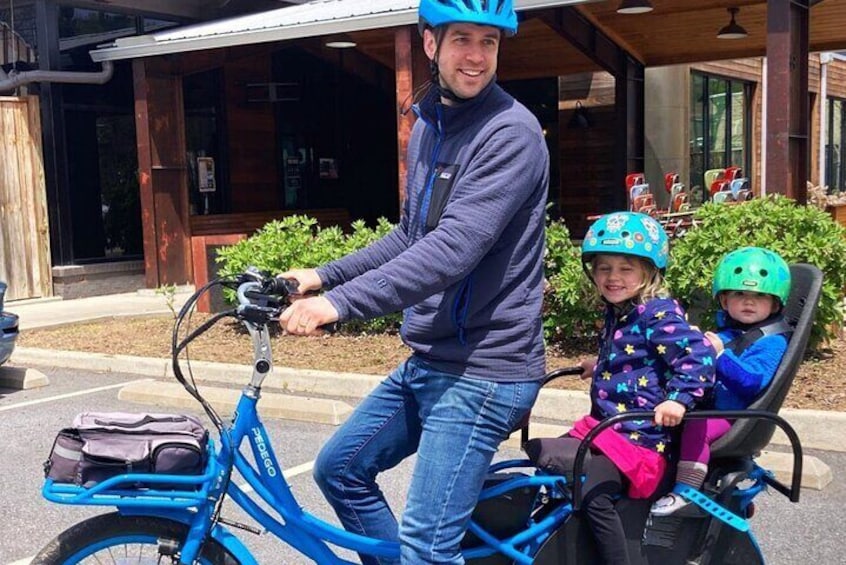 Father looking back at his children seated on a cargo e-bike