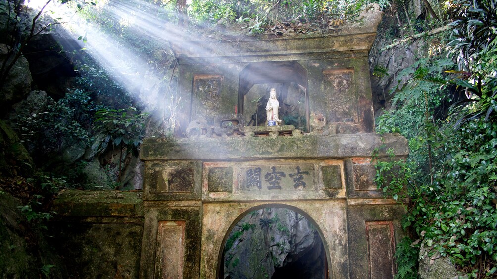 Light shining through the trees on an ancient archway in the woods in Da Nang