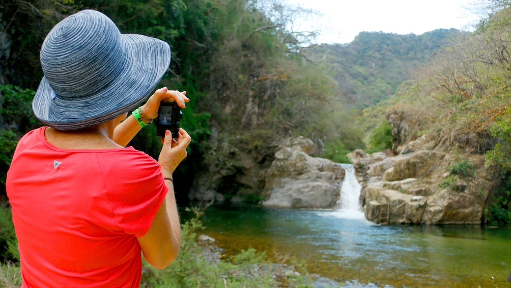 Woman taking a picture of waterfall