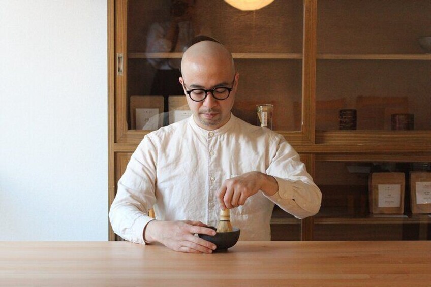 Host whisking the matcha green tea powder