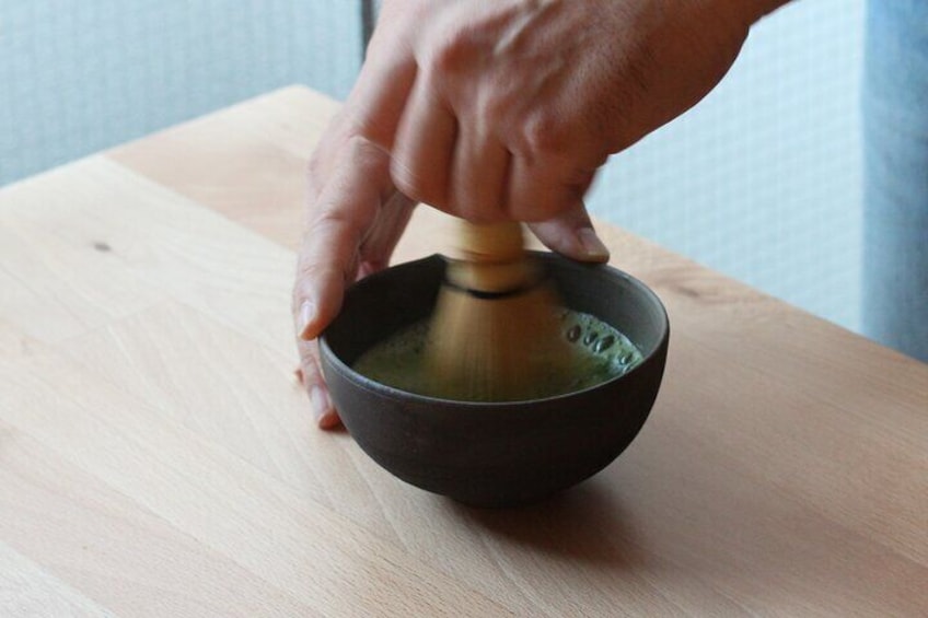 Host making matcha green tea powder