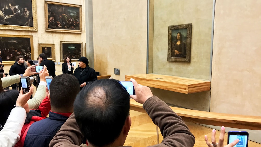 Group photographing the Mona Lisa on guided tour of the Louvre Museum in Paris