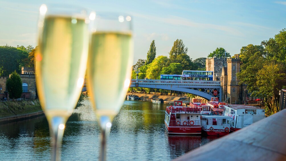 Two champagne flutes with Cruise boats in the background