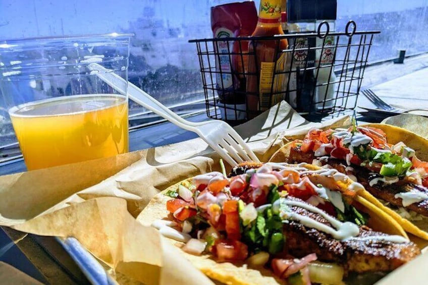 A delectable duo: Seafood tacos and a refreshing brew, savoring the flavors with a breathtaking marina view.
