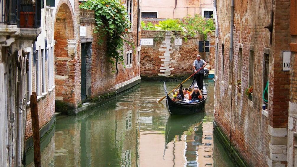 Single gondola paddles down quiet waterway in Venice