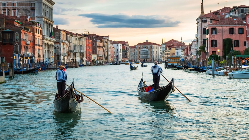 Two gondolas paddling down waterway in Venice