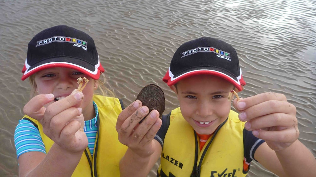 Show item 5 of 7. Children hold up their findings while out kayaking in Batemans Bay