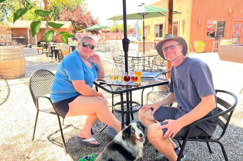 Guests and their dog enjoying the beers and views of Sedona's majestic red rock formations from the outdoor patio at Vino Di Sedona.