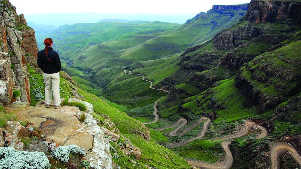 Tourist stands at the top of Sani Pass looking down at the road in Lesotho