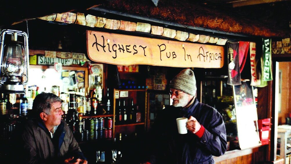 Man enjoys drink and talks to bartender at the Highest Pub in Africa in Lesotho