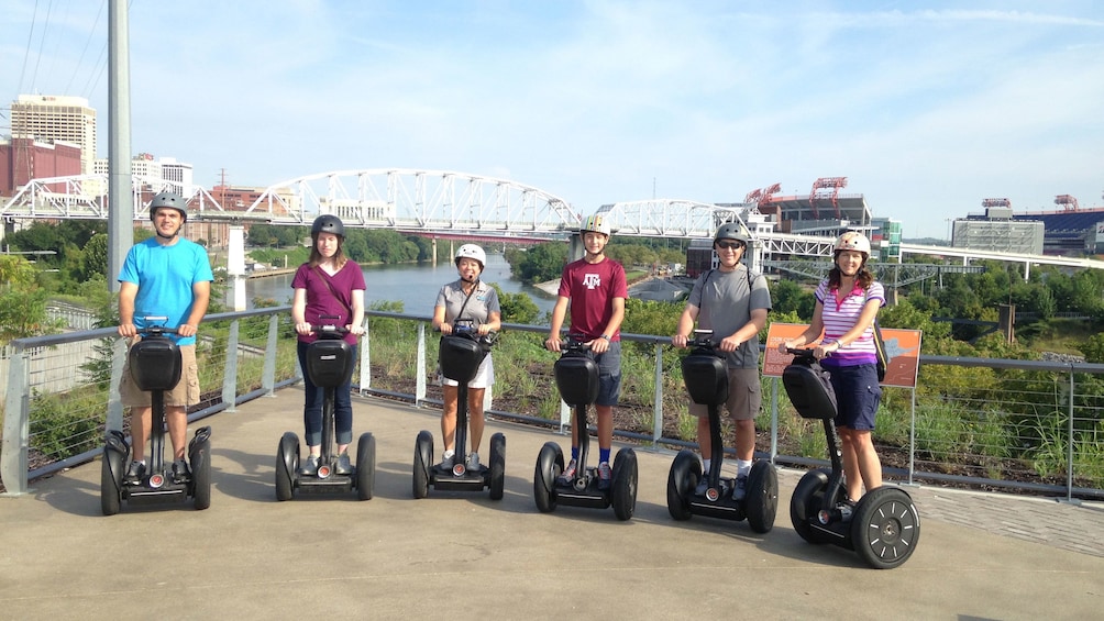 Group poses on segways with bridge in background for segway tour in Nashville