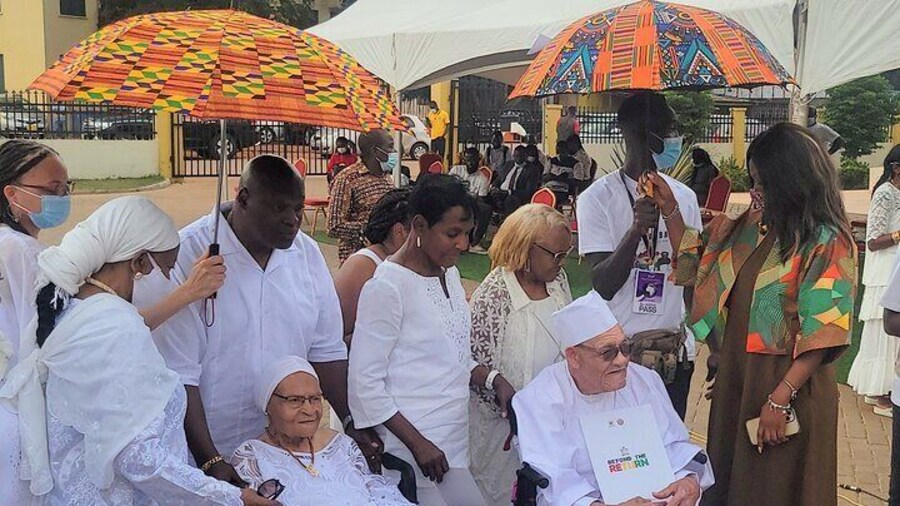 An elderly African American after their traditional naming ceremony with their certificates