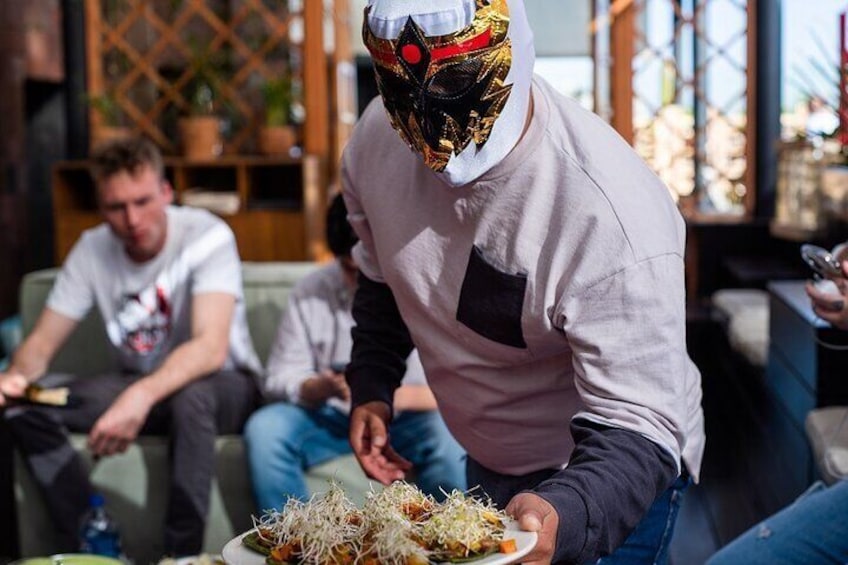 The experience includes tasting tacos, mezcal, class on Lucha Libre, one-way transportation and entry to the Arena México