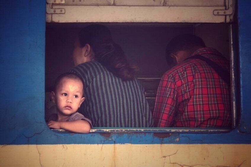 The Burmese kid sitting by the window of circle train in Yangon .