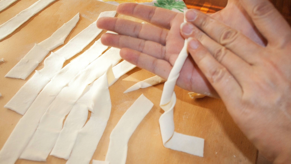 Show item 4 of 8. Pasta being rolled during cooking class near Alghero