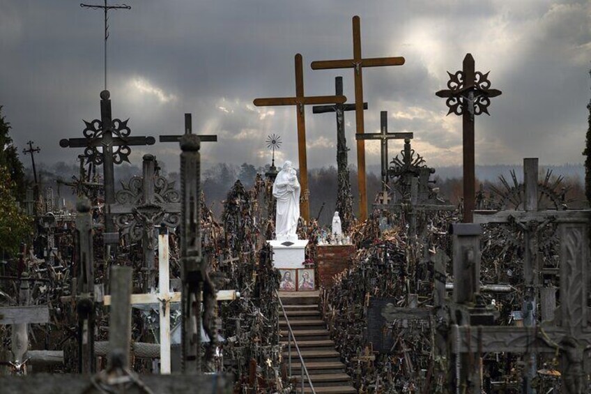 Top of Hill of crosses with dark sky and white sculpture