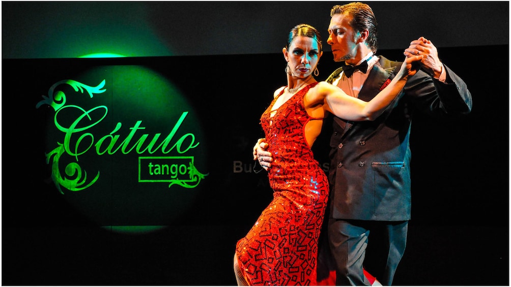 Man and woman dancing the Tango next to Cátulo Tango Show sign
