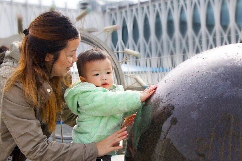 A woman and young child explore the Water Works exhibit's spinning granite ball in PacSci's courtyard.