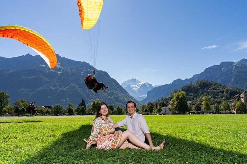 Center of Interlaken with the greenfield Höhematte and paragliders