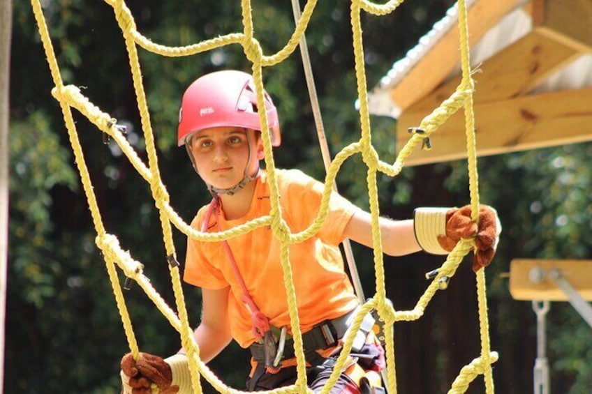 Child climbing the rope ladder element on the Gully Challenge Course 