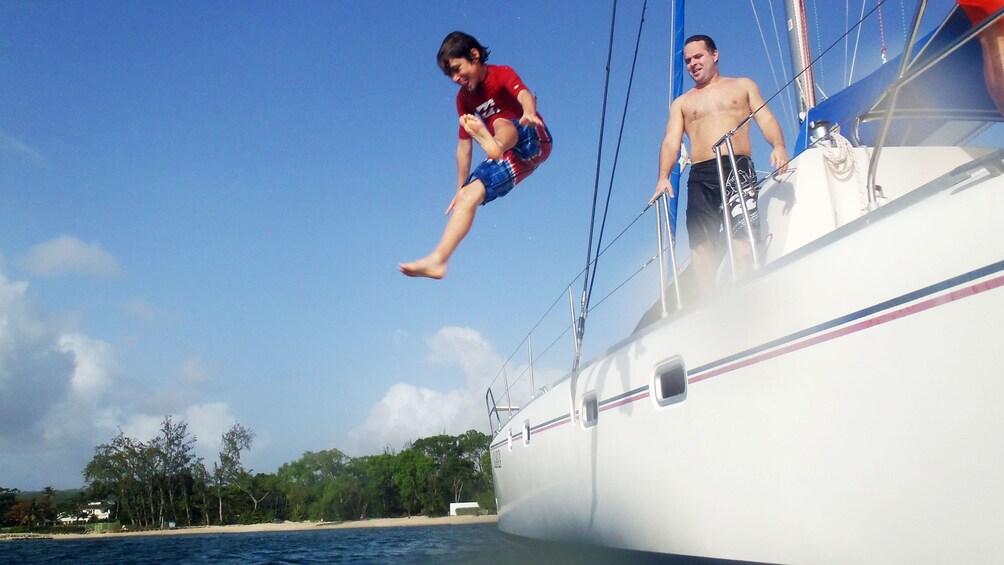 Boy jumping from sailboat to water in Barbados