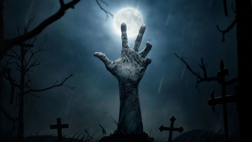 Hand emerging from a grave on a full moon night