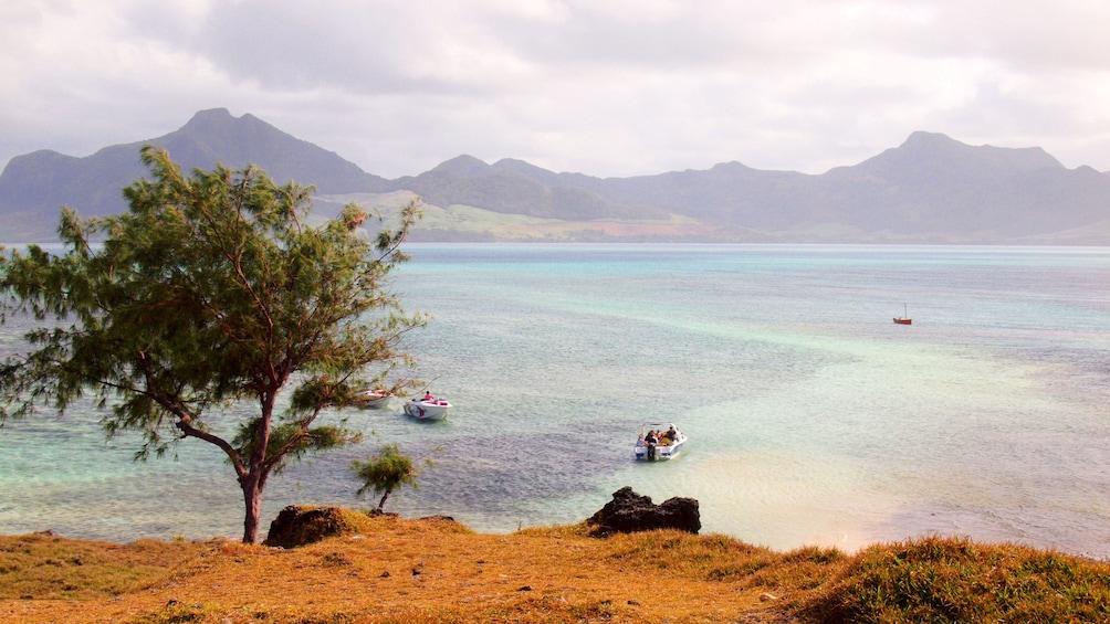 View from peninsula of tour speedboats float on clear waters in Mauritius