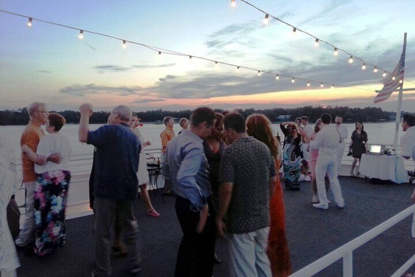 Guests dancing on the open-air sky deck aboard the SOLARIS dinner cruise