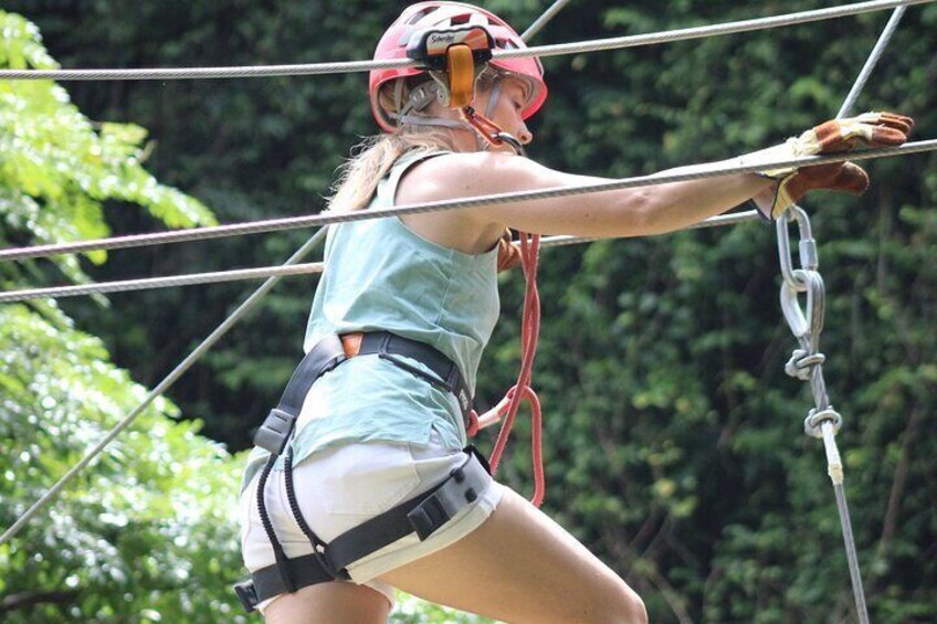 Mom climbing across the block ladder on the Gully Challenge Course at the Harrison's Cave Eco-Adventure Park