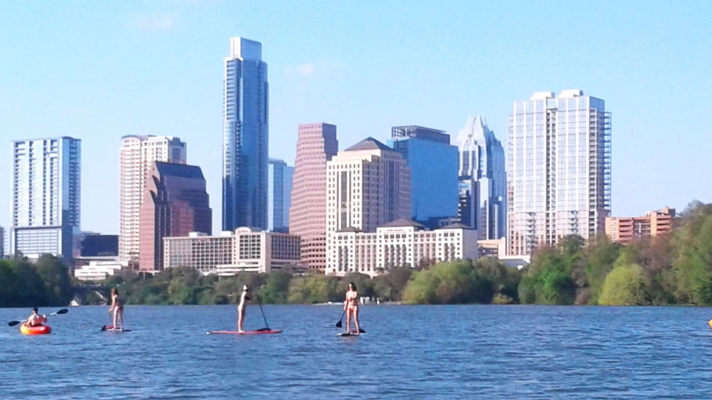Kayakers and paddle boarders on river with Austin skyline in background
