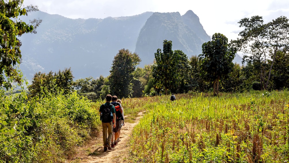 Hiking group trekking down trail in Nam Khan River Valley in Laos