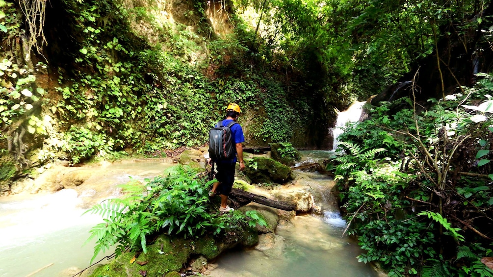 Hiker trekking through river in Laos