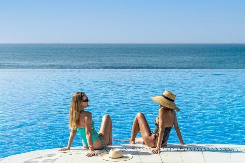 Two guests enjoy the infinity pool and sea views