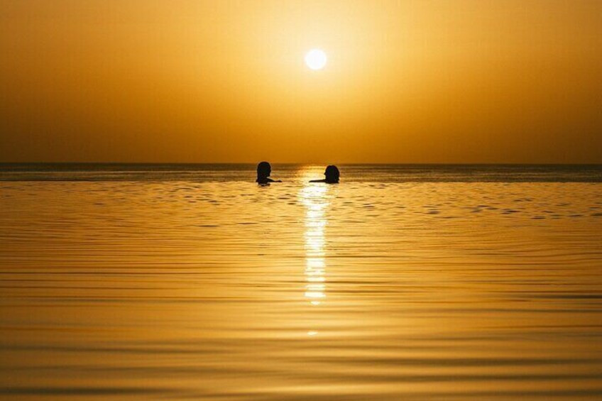 Two people watch the sunset in the pool