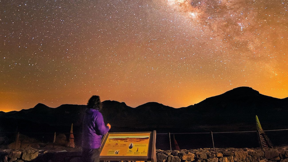 Foto 5 van 4. Woman looking up at the stars over Teide volcano