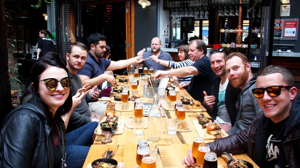 Group enjoying food and beer on pub walk in Sydney