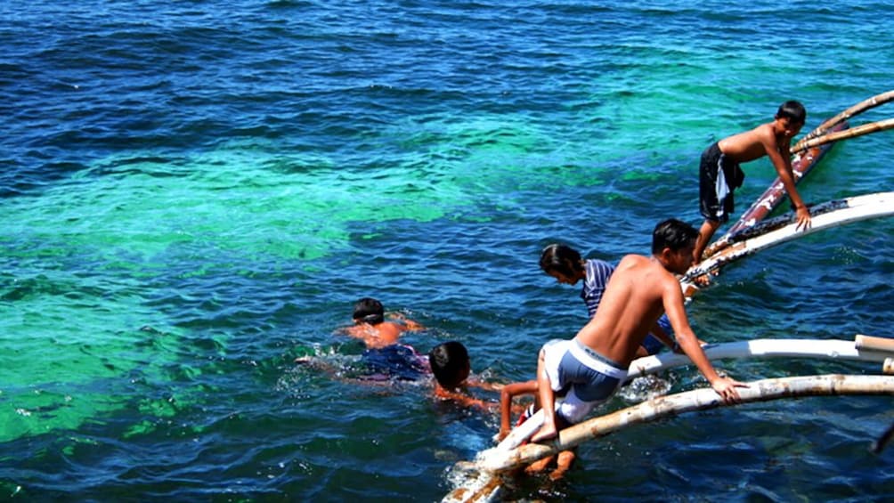 Group of people swimming  next to a boat