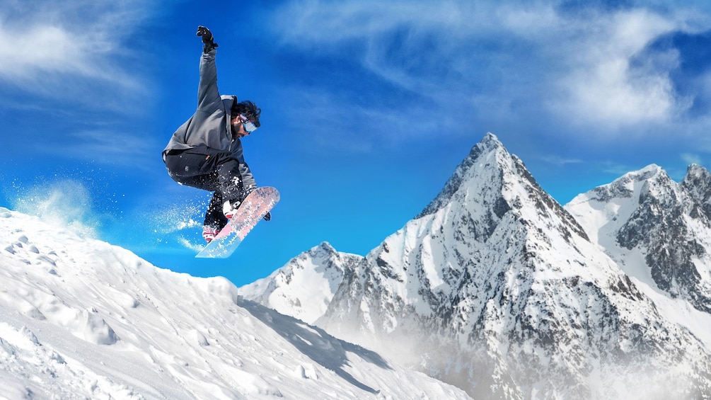 Man on snowboard in mid jump on slopes in Mammoth Lakes, California