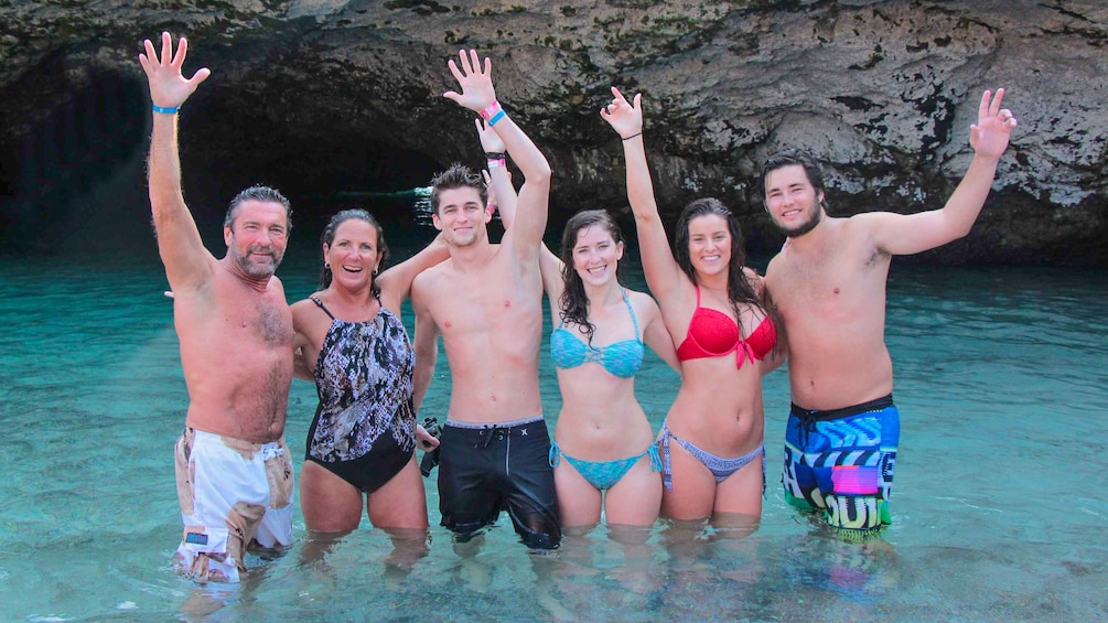 Group of people posing for a picture while standing in the water of a hidden island beach in Nayarit, Mexico