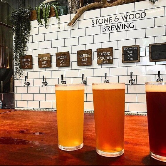 Show item 2 of 3. Three pints of different colored beer on a bar top with a wall of beer taps in the background